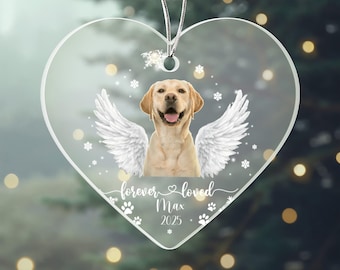 May include: Clear heart-shaped ornament with a yellow Labrador Retriever, angel wings, and the text "forever loved Max 2025". The design includes paw prints and snowflakes. The ornament hangs from a silver string.