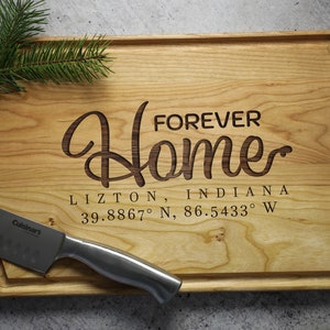 May include: A wooden cutting board with the text "Forever Home Lizton, Indiana 39.8867° N, 86.5433° W" engraved on it.