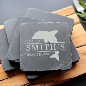 May include: Set of four black slate coasters with a white dolphin design and the text "EST. 2025 SMITH'S BEACH HOUSE".