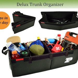 May include: Black trunk organizer with multiple compartments, holding various items like a water bottle, hat, and first aid kit. The organizer has a Velcro closure and a logo on the side. The text "Delux Trunk Organizer" is at the top.