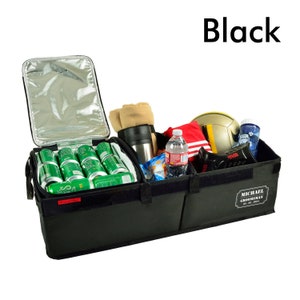 May include: Black car trunk organizer with multiple compartments. The organizer is filled with items such as drinks, snacks, a blanket, and a water bottle. The organizer has a personalized label that says "Michael Groomsman".