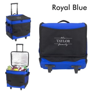 May include: Royal blue and black rolling cooler bag with the text "the TAYLOR family" in white. The cooler has a telescoping handle, side pockets, and wheels. The cooler is open in one image, revealing food and drinks.