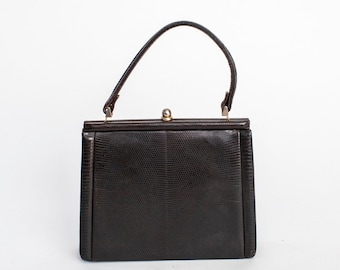 May include: A dark brown leather handbag with a top clasp closure and a single handle.
