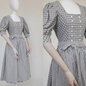 Puede incluir: Un vestido de dirndl a rayas blancas y negras con un corpiño blanco con un patrón de cuadros negros y blancos. El corpiño tiene un escote cuadrado y una fila de botones blancos en la parte delantera.