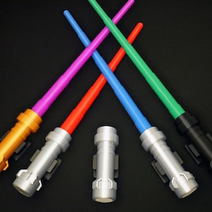 May include: Five toy lightsabers in different colors: purple, red, blue, green, and black. The lightsabers have silver handles and are arranged in a criss-cross pattern.