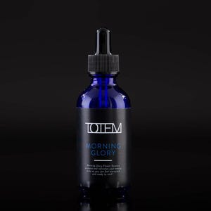 May include: A blue glass bottle with a black dropper top and a black label that reads "TOTEM MORNING GLORY Morning Glory Flower Essence awakens and refreshes your energy body so you can feel energized and ready to rock."