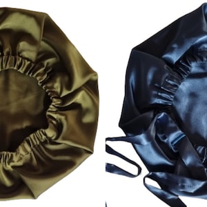 May include: Two satin bonnets, one olive green and one navy blue, are displayed. Each bonnet has a gathered elastic edge and long ties. The bonnets are designed to protect hair while sleeping.