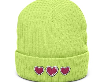 May include: A neon green beanie with a ribbed knit texture. The folded brim features three embroidered pink hearts with white outlines, arranged horizontally. This hat is a stylish accessory for casual wear.