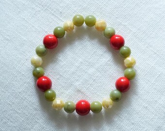 May include: A beaded bracelet featuring red, green, and yellow beads. The bracelet is made of round and faceted beads, strung together to form a flexible band. The beads are arranged in a repeating pattern.