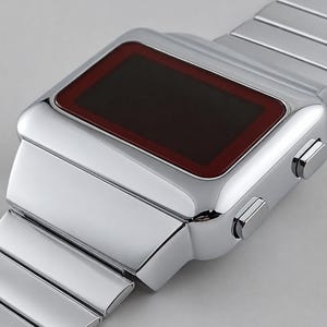 May include: A digital wristwatch with a polished silver-tone metal case and a matching link bracelet. The rectangular watch face features a dark, deep red display screen framed by a smooth, metallic border, with two rectangular buttons on the side.