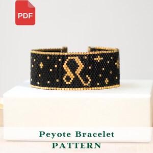 Könnte beinhalten: Schwarzes Peyote-Armbandmuster mit goldenen Akzenten und einem goldenen Löwen-Symbol. Das Armband liegt auf einer weißen Oberfläche. Der Text "Peyote Bracelet PATTERN" steht darunter. Ein PDF-Symbol befindet sich oben links.