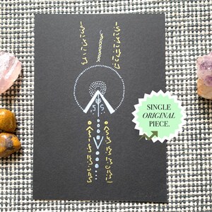 Könnte beinhalten: Eine rechteckige schwarze Karte mit einem weißen und goldenen geometrischen Design, das einen zentralen Kreis, Pfeile und vertikale Symbole zeigt. Ein hellgrüner sternförmiger Aufkleber mit dem Text "SINGLE ORIGINAL PIECE." klebt rechts auf der Karte.