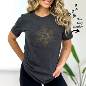 May include: A dark grey heather t-shirt with a gold geometric design on the front. The design is a complex pattern of overlapping circles and lines.