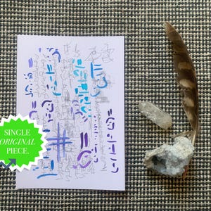 May include: A white paper with blue and purple abstract art and the text "SINGLE ORIGINAL PIECE." A feather, a clear quartz crystal, and a cluster of small crystals are also present. The items are arranged on a patterned surface.