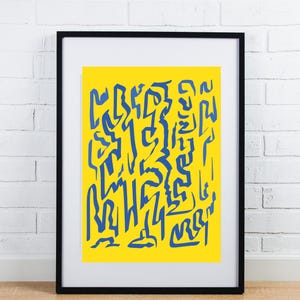 May include: Abstract art print featuring a vibrant yellow background with blue, stylized shapes. The artwork is framed in a black frame and displayed against a white brick wall. The print's design is modern and eye-catching.
