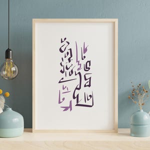 May include: A framed art print featuring abstract purple calligraphy on a white background. The artwork is displayed in a light wood frame and rests on a shelf with decorative vases and a hanging light bulb.