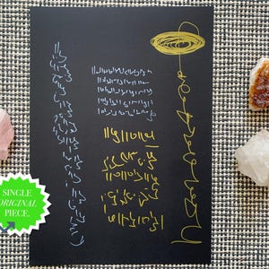Könnte beinhalten: Ein schwarzer rechteckiger Druck mit handgezeichneten weißen und goldenen Symbolen und Text, begleitet von einem rosa Rosenquarz, einem klaren Quarz und einem bernsteinfarbenen Kristall sowie einem grünen Sternaufkleber mit SINGLE ORIGINAL PIECE.