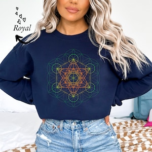 Puede incluir: Una sudadera azul marino con un diseño geométrico en tonos de verde, naranja y amarillo. El diseño es un patrón complejo de círculos y líneas superpuestos, creando una apariencia visualmente interesante e intrincada.