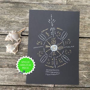 May include: A rectangular black paper print featuring a circular white and gold ink design with radiating lines and abstract symbols. A green star-shaped sticker with the text SINGLE ORIGINAL PIECE is attached to the lower left corner of the print.