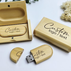 Può includere: Due chiavette USB in legno con un logo e un testo personalizzati incisi. Una chiavetta è in una scatola di legno con un coperchio. L'altra chiavetta è su una superficie bianca.