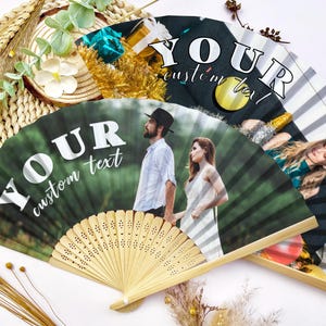 May include: Three custom printed hand fans with bamboo handles. The fans feature personalized photos and the text "YOUR custom text" in white. One fan has a photo of a couple, another has a photo of a person, and the third has a black and white striped design.