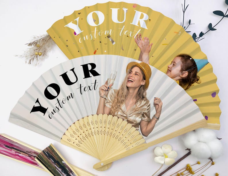 May include: Two personalized paper fans with the text "YOUR custom text". One fan is white with a photo of a woman holding a champagne glass. The other fan is yellow with confetti.