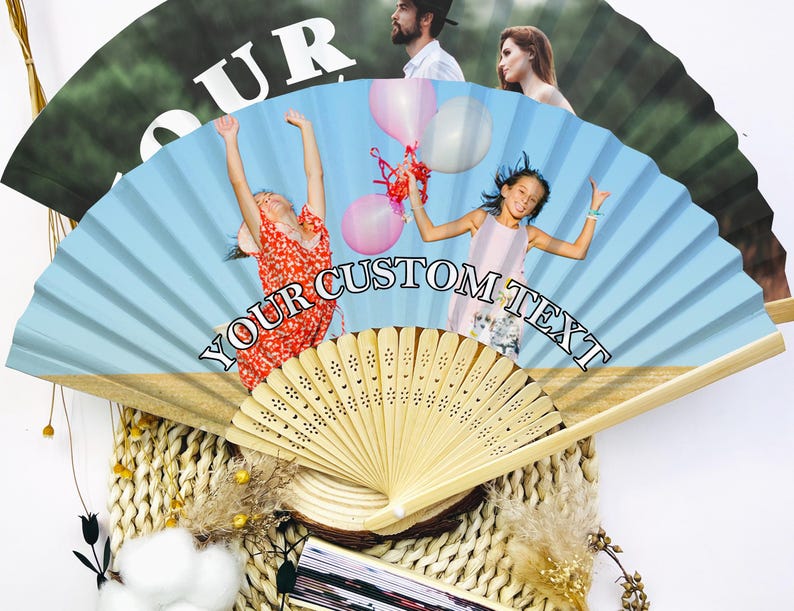 May include: A custom-printed hand fan with a light blue background and the text "YOUR CUSTOM TEXT". The fan features images of people and children holding balloons. The fan is made of wood and paper.