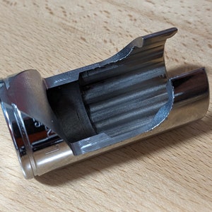 May include: A silver metal socket wrench with a split end and a ribbed interior. The wrench is designed to remove or install a specific type of nut or bolt.