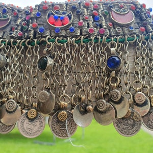 May include: A silver and gold necklace with a chain fringe and coin-like charms. The necklace is decorated with red, blue, and green gemstones.