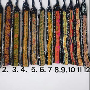 May include: Twelve colourful beaded and embroidered trim strips, each with a different pattern and colour combination. The strips are arranged in a row, numbered 2 through 12.