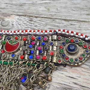 May include: A silver and gold colored necklace with red, blue, and green glass beads. The necklace has a fringe of silver chains and beads.