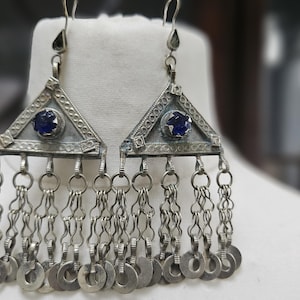 Puede incluir: Un par de pendientes de plata con piedras de cristal azul y cadenas colgantes de anillos de plata.