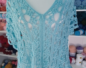 Peut inclure: Un haut en crochet bleu clair avec un motif ajouré délicat. Le haut a un col en V et des manches courtes.