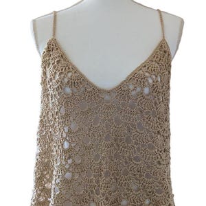 May include: A beige crochet tank top with a V-neck and thin straps. The top is made of a delicate, open-stitch pattern.