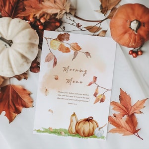 May include: A watercolour illustration of an autumn-themed menu card with a quote about honouring your father and mother. The card features a branch with orange and yellow leaves, a small pumpkin, and a gourd. The background is a soft orange watercolour wash.