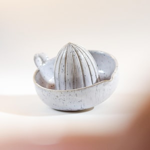 Può includere: Spremitore per agrumi in ceramica maculata. Lo spremiagrumi grigio chiaro ha un alesatore scanalato e un piccolo manico. La ciotola ha un bordo largo e un beccuccio. Accessorio da cucina.