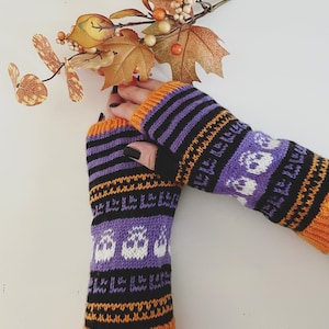 May include: A pair of purple, orange and black knitted fingerless gloves with a white ghost pattern.