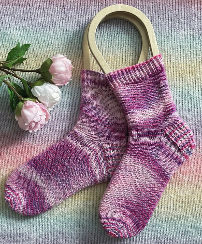 May include: A pair of pink and purple striped knitted socks with a wooden sock blocker.