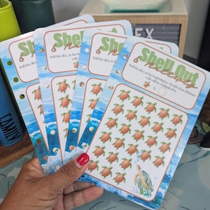 May include: Four rectangular paper planner inserts featuring a sea turtle theme with blue ocean waves at the bottom. The text reads Shell Out Multiply, Roll the dice at the beginning to decide what all future rolls will be multiplied by, and X O.