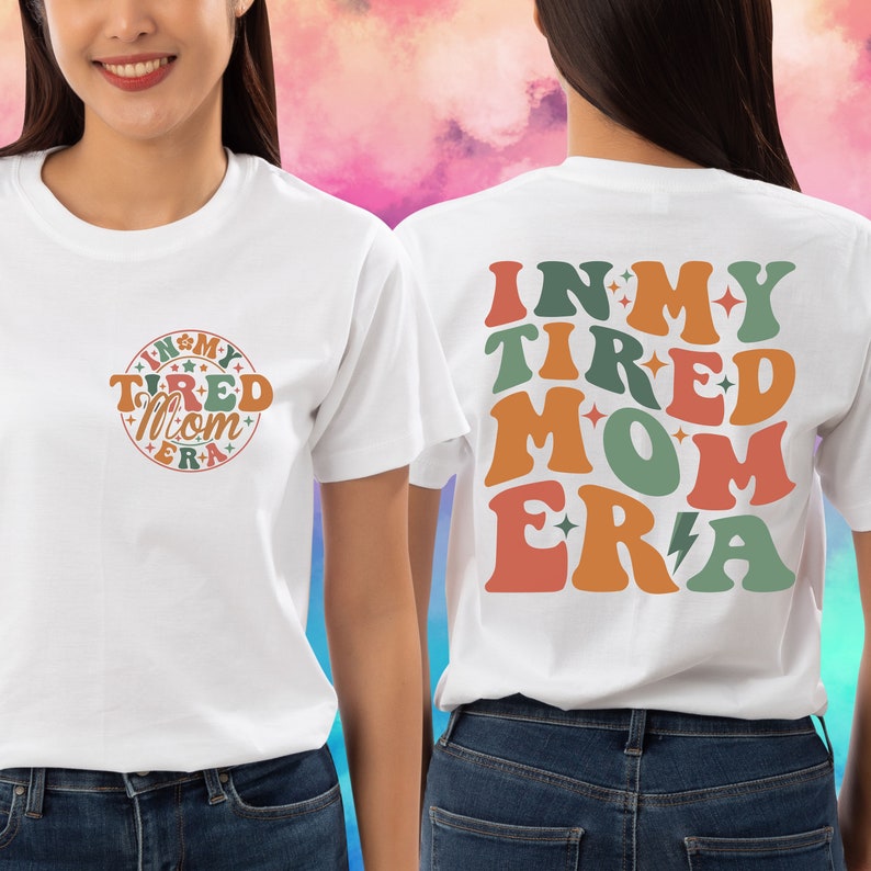 May include: White t-shirt with the text "In My Tired Mom Era" in a retro font with stars and lightning bolts. The text is in shades of orange, green, and red.