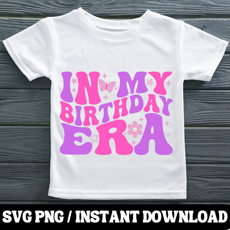 Puede incluir: Una camiseta blanca con un dise&ntilde;o rosa y morado que dice "In My Birthday Era". El dise&ntilde;o incluye mariposas, estrellas y flores.