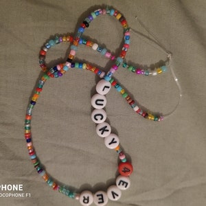 May include: A colorful beaded necklace with white letter beads spelling out "LUCKY" and "EVER".