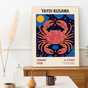 May include: A poster featuring a red and white crab with polka dots on a blue background with yellow and blue circles. The poster is titled "Yayoi Kusama" and includes the text "A-Crab" and "Tokyo 1998".