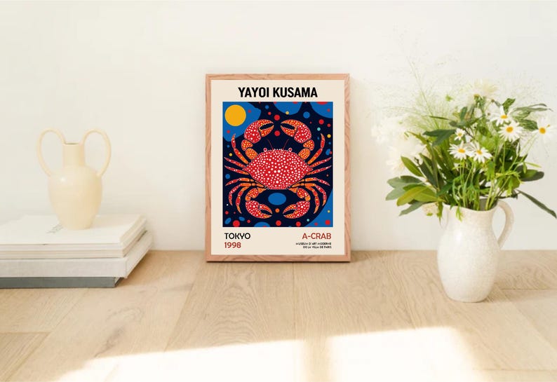May include: A framed print of a red and white crab with black polka dots on a blue background with white polka dots. The print is titled "A-Crab" and includes the artist's name "Yayoi Kusama" and the date "Tokyo 1998".