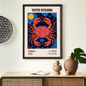 May include: A colorful poster featuring a red crab with white polka dots on a blue background with yellow and red circles. The poster is titled "Yayoi Kusama A-Crab" and includes the text "Tokyo 1998".