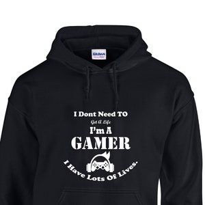 May include: Black hooded sweatshirt with white text that reads "I Don't Need To Get A Life I'm A Gamer I Have Lots Of Lives." The text is surrounded by a graphic of a video game controller with headphones.