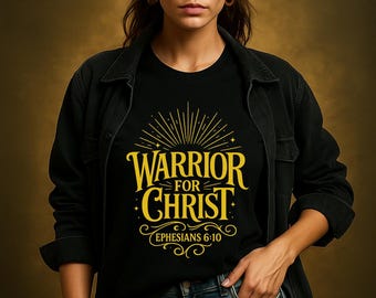 Op de afbeelding: Zwart T-shirt met gouden tekst "WARRIOR FOR CHRIST" en de Bijbelverwijzing Efeziërs 6:10. Het shirt wordt gedragen met een zwarte jas en een blauwe jeans.