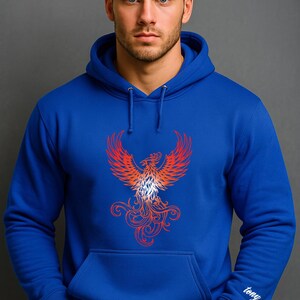 A man stands confidently against a solid gray background wearing a royal blue hoodie. The front of the hoodie features a bold red and orange phoenix graphic with intricate, flame-like detailing. On the right sleeve cuff, the name "tony" is embroidered in a small, white cursive font. The model has short dark hair, a trimmed beard, and a serious expression, with his hands tucked into the front pocket of the hoodie.