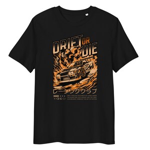 May include: Black t-shirt with an orange graphic of a car drifting in flames. The text "Drift or Die" is above the car and "レーシングクラブ" is below the car. The text below the car reads "Drift through the streets of Japan, where the roads are our canvas, and the cars our brushes embrace the art of motion."