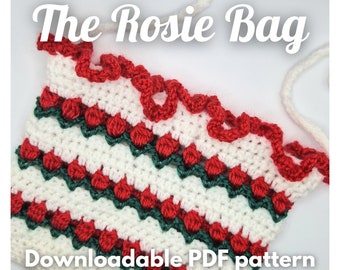 May include: A crochet bag pattern featuring a white, red, and green design with a scalloped edge. The pattern is called "The Rosie Bag" and is downloadable as a PDF.